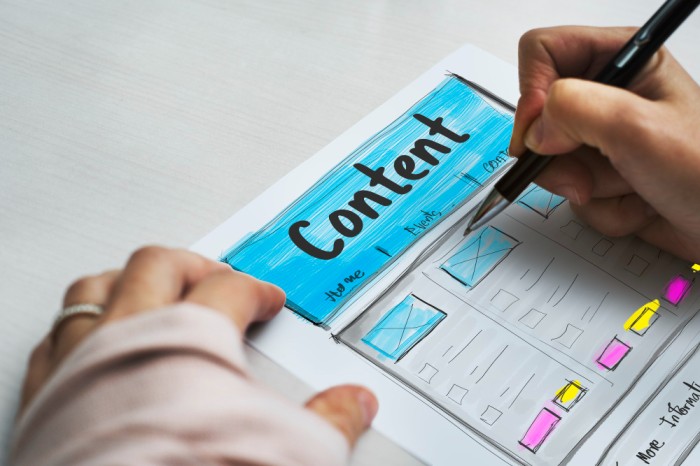 A person sketching a webpage layout on paper with the word "Content" at the top, representing content marketing and content creation planning.